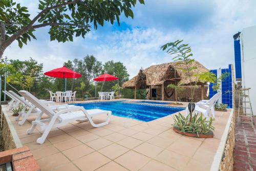 une villa avec une piscine, des chaises et un toit de chaume dans l'établissement Cabana Costa Azul, à Coveñas
