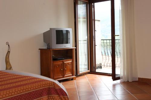a bedroom with a television on a dresser with a balcony at B&B Villa Ursa Major in Vico Equense