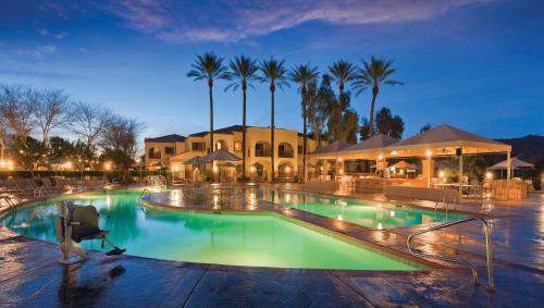 a swimming pool with palm trees and a building at The Legacy Golf Resort in Phoenix