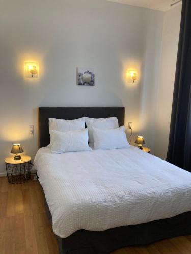1 dormitorio con 1 cama grande con sábanas y almohadas blancas en Appart Aux deux Colombes avec Balcon et Garage en Pamiers