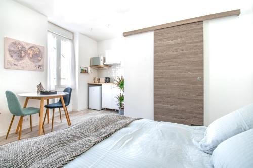 une chambre avec un lit, une table et des chaises dans l'établissement Studio Cosy sur île de Nantes - Proche Tram 2 et 3, à Nantes
