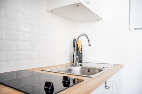 - une cuisine avec un évier et un mur blanc dans l'établissement Studio Cosy sur île de Nantes - Proche Tram 2 et 3, à Nantes