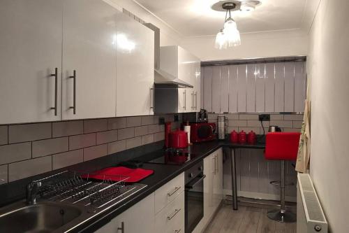 a kitchen with white cabinets and a stainless steel sink at Tranquil Welsh Mountain Gem, Abertillery, Wales in Abertillery