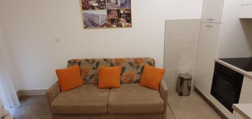 sala de estar con sofá y almohadas de color naranja en Glambeauty1, en Jagodina