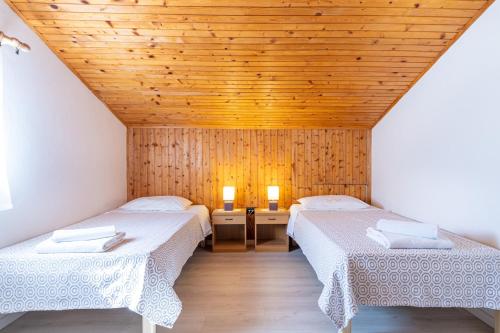 two beds in a room with a wooden ceiling at Apartments Ada near the Sea in Poreč