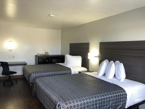 a hotel room with two beds and a desk at Sky Palace Inn By Jasper Near AT & T Center in San Antonio