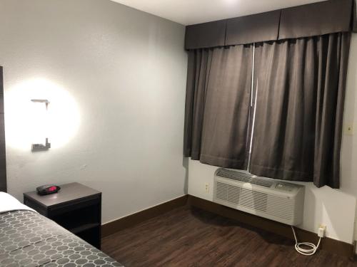a bedroom with a bed and a window with a air conditioner at Sky Palace Inn By Jasper Near AT & T Center in San Antonio