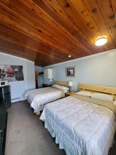 two beds in a room with a wooden ceiling at Bio Vista Motel in Wainwright