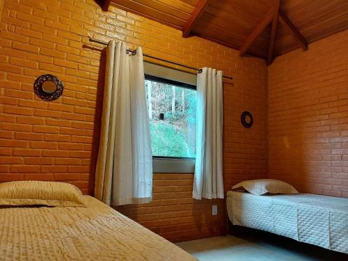 Un dormitorio con dos camas y una ventana. en Villa da Serra Ibitipoca chalé família - 700m do centrinho, en Conceição da Ibitipoca
