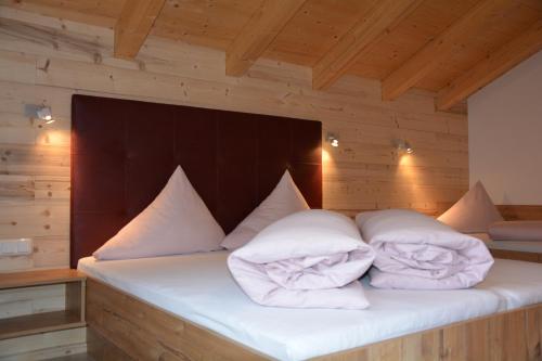 カップルにあるTischlerei Rudigier Vermietungの木製の部屋のベッド(白い枕付)
