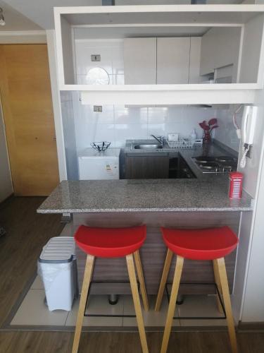 a kitchen with two red stools at a counter at 2 Torres Calama in Calama