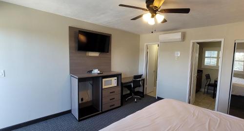 a bedroom with a bed and a desk with a tv at Beachwalker Inn & Suites in Pismo Beach