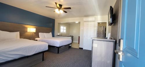 a hotel room with two beds and a ceiling fan at Beachwalker Inn & Suites in Pismo Beach