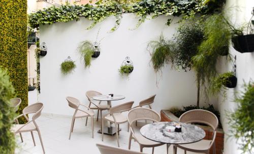 een patio met tafels en stoelen en een muur met planten bij Golden City Hotel & Spa, Tirana in Tirana