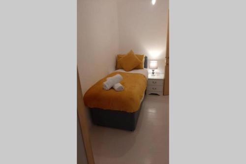 um pequeno quarto com uma cama com um cobertor amarelo em Modern 2 Bed Apartment by BellaLiving em Luton