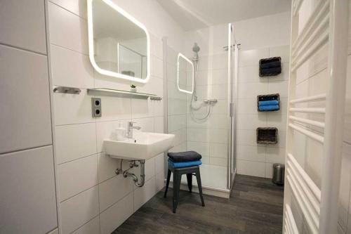 ein weißes Bad mit einem Waschbecken und einer Dusche in der Unterkunft Ferienwohnung 41 mit perfekter Ausstattung, Residenz Meeresbrandung Duhnen in Cuxhaven