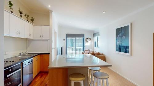 una cocina con armarios blancos y una isla de cocina con taburetes en Valley View 303 AMS Mt Buller, en Mount Buller