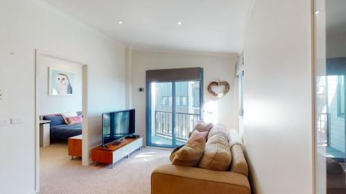 Una sala de estar con un sofá y un televisor. en Valley View 303 AMS Mt Buller, en Mount Buller