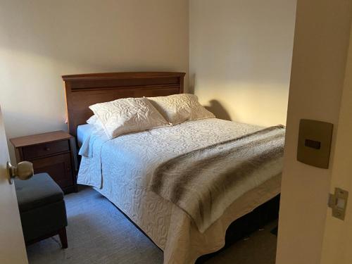 1 dormitorio con cama blanca y cabecero de madera en Departamento Temuco Full Equipado en Temuco