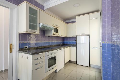 a kitchen with white cabinets and blue tiles at BeachFront in Puerto Mogán in Puerto de Mogán