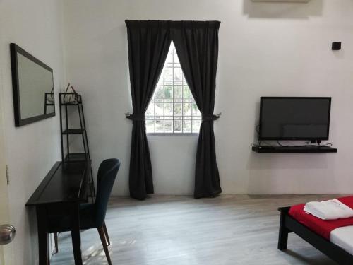 un soggiorno con scrivania, finestra e TV di RoomStay Hj Esmon Parit Raja UTHM a Parit Raja
