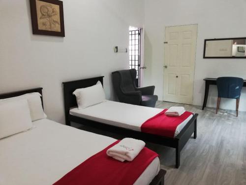 una camera d'albergo con due letti e una sedia di RoomStay Hj Esmon Parit Raja UTHM a Parit Raja