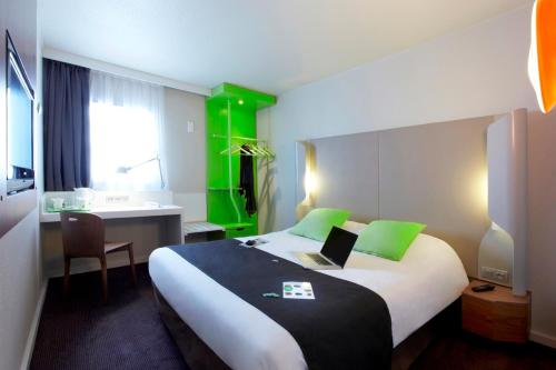 une chambre d'hôtel avec un lit et un ordinateur portable. dans l'établissement Campanile Paris Porte d'Italie - Le Kremlin Bicêtre, au Kremlin-Bicêtre