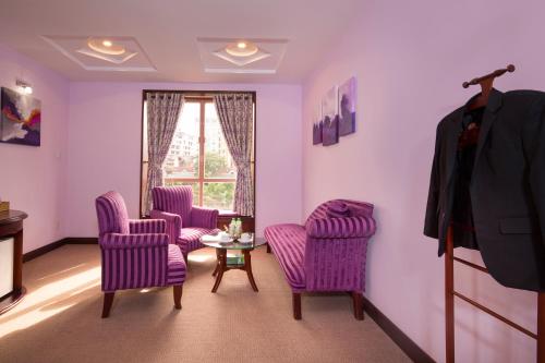 a living room with purple chairs and a table at TTC Hotel - Da Lat in Da Lat
