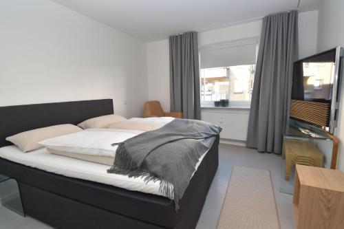 um quarto com uma cama e uma televisão de ecrã plano em fewo1846 - FoerdeView - luxuriöse Wohnung mit 2 Schlafzimmern und Balkon mit Hafenblick em Flensburg