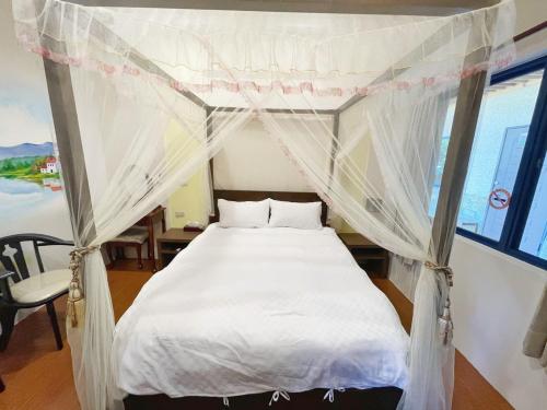 a bed with a canopy in a room at 花宿 民宿 in Xiaoliuqiu