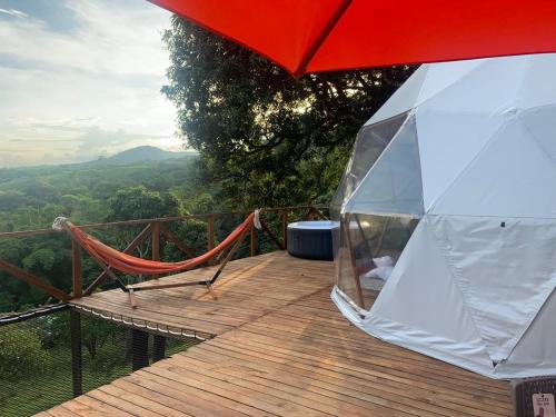 a wooden deck with a hammock and a red umbrella at Eco-Glamping Shalom in Mariquita