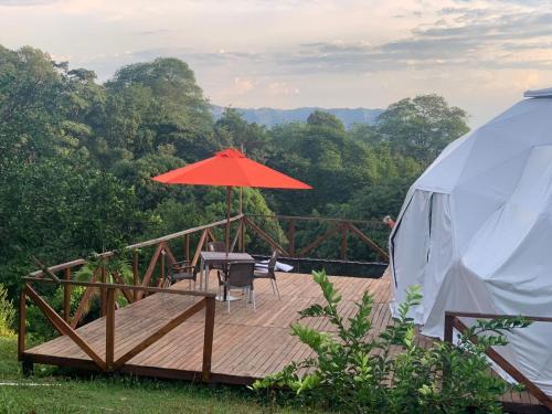 a wooden deck with a table and an umbrella at Eco-Glamping Shalom in Mariquita