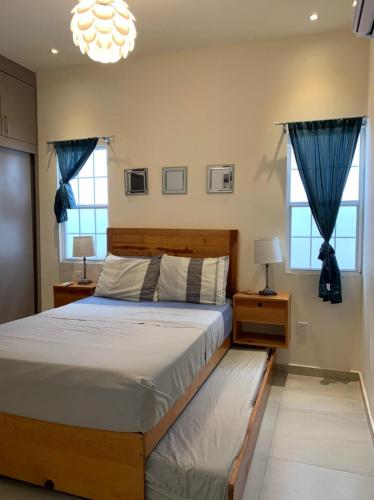 a bedroom with a large bed and two windows at Beautiful 3 BR/3.5 bath Home@Selvanova in Playa del Carmen