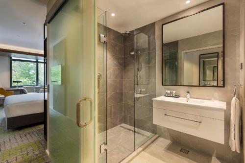 a bathroom with a shower and a sink and a mirror at Mercure Auckland Queen Street in Auckland