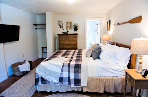 a bedroom with a bed and a dresser and a television at Inn on Golden Pond in Holderness