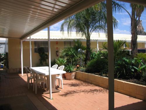 a patio with a table and chairs and palm trees at THE MEYERS HOUSE - ACCOMMODATION in Kalgoorlie