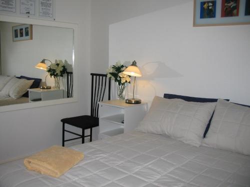 a bedroom with a white bed with a mirror and a chair at THE MEYERS HOUSE - ACCOMMODATION in Kalgoorlie