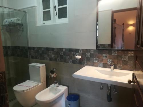 a bathroom with a sink and a toilet and a mirror at The Villa Hotel in Unawatuna