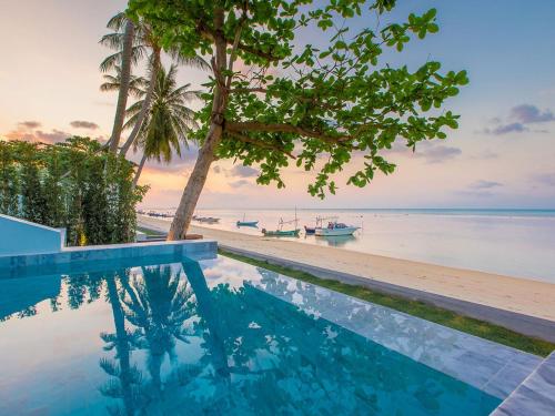a swimming pool next to a beach with a boat at White Whale Beachfront Pool Villa in Ban Bang Po