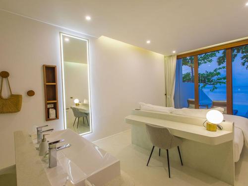a white bathroom with a sink and a desk at White Whale Beachfront Pool Villa in Ban Bang Po
