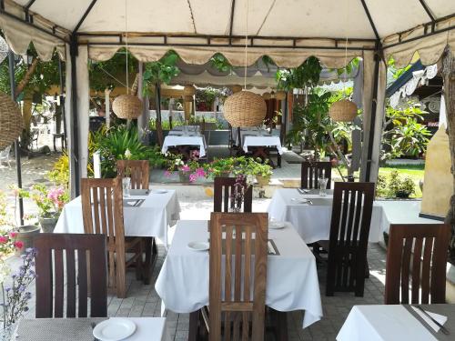 restauracja z białymi stołami i krzesłami pod namiotem w obiekcie The Villa Hotel w mieście Unawatuna