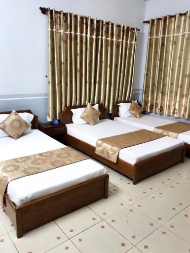 three beds in a room with curtains at Huyen Tran Hotel in Can Tho