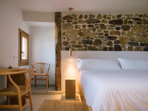 a bedroom with a bed and a table and a stone wall at Hotel Nafarrola - Gastronomy & Wine in Bermeo