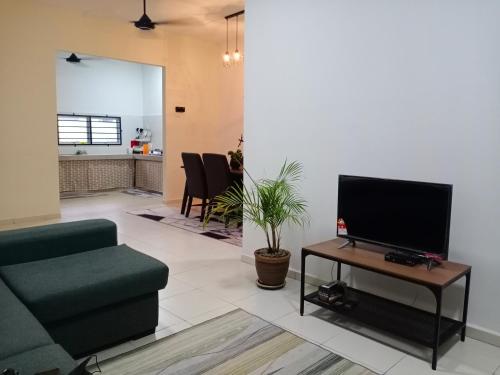 een woonkamer met een bank en een tv op een tafel bij Kyra's Homestay Melaka in Merlimau