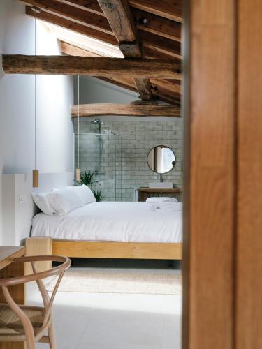 a bedroom with a bed with white sheets and a mirror at Hotel Nafarrola - Gastronomy & Wine in Bermeo