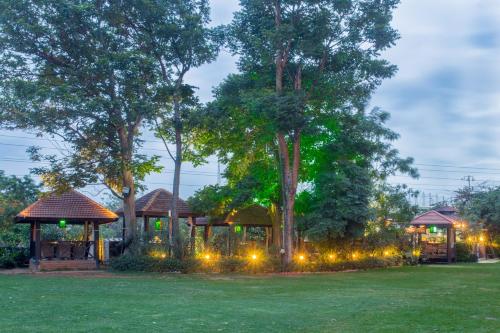 a garden with a gazebo and trees at night at Hotel Royal Orchid Bangalore in Bengaluru
