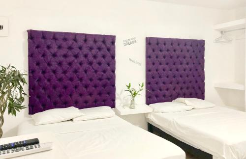 two beds in a room with a purple wall at Zyan Rooms in Villahermosa