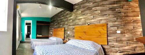 a room with two beds and a stone wall at Zyan Rooms in Villahermosa