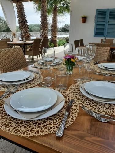 a wooden table with plates and wine glasses on it at Turismo Rural Biniati des Pi in Sant Lluis