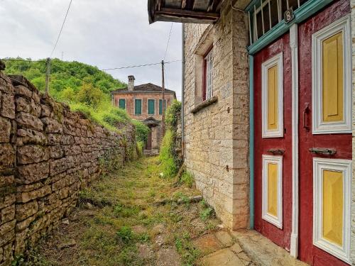 an alley with a red door and a stone wall at Aithrio in Dilofo